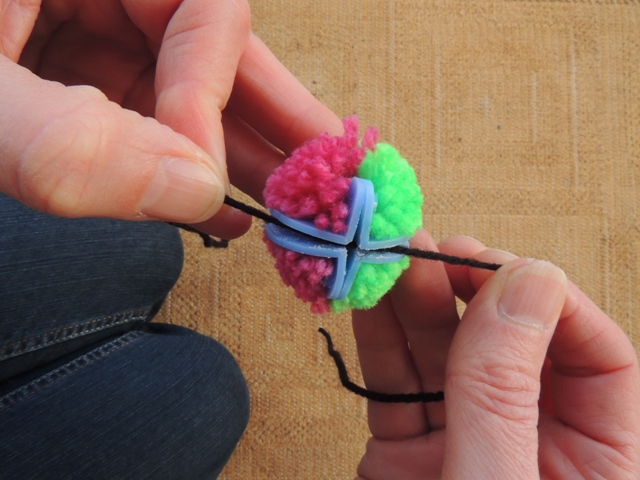 Wind a length of wool around the pom pom where you have cut.
