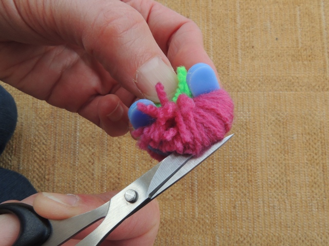 Place the blade of your scissors between the two halves of the circle and start to cut the wool - gradually work your way around until your pom pom....